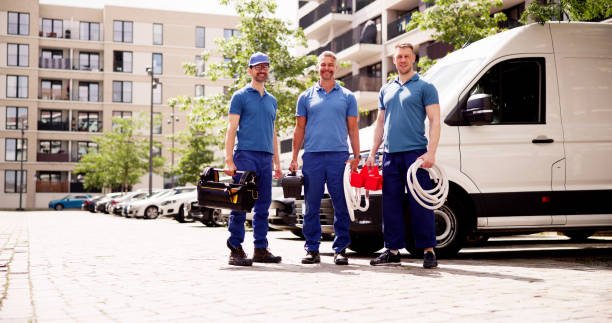 Three men in blue shirts stand beside a van, smiling and engaged in conversation, representing affordable handyman services near you.