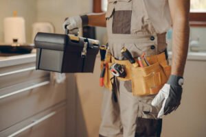 A man in overalls stands holding a toolbox, ready for work, representing the best handyman service in Scottsdale.
