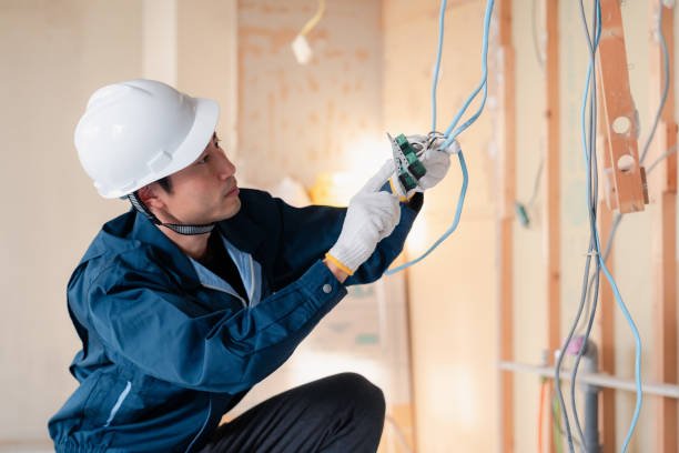 A man wearing a hard hat and helmet is focused on repairing electrical wires, showcasing the expertise of a home improvement handyman in Phoenix.