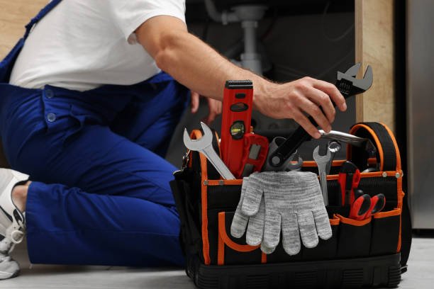 A man stands holding a tool bag filled with various tools, ready for an emergency plumbing service in Phoenix.