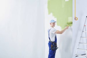 A painting contractor in Tucson, AZ confidently painting a wall green with a brush, delivering a smooth, professional finish.